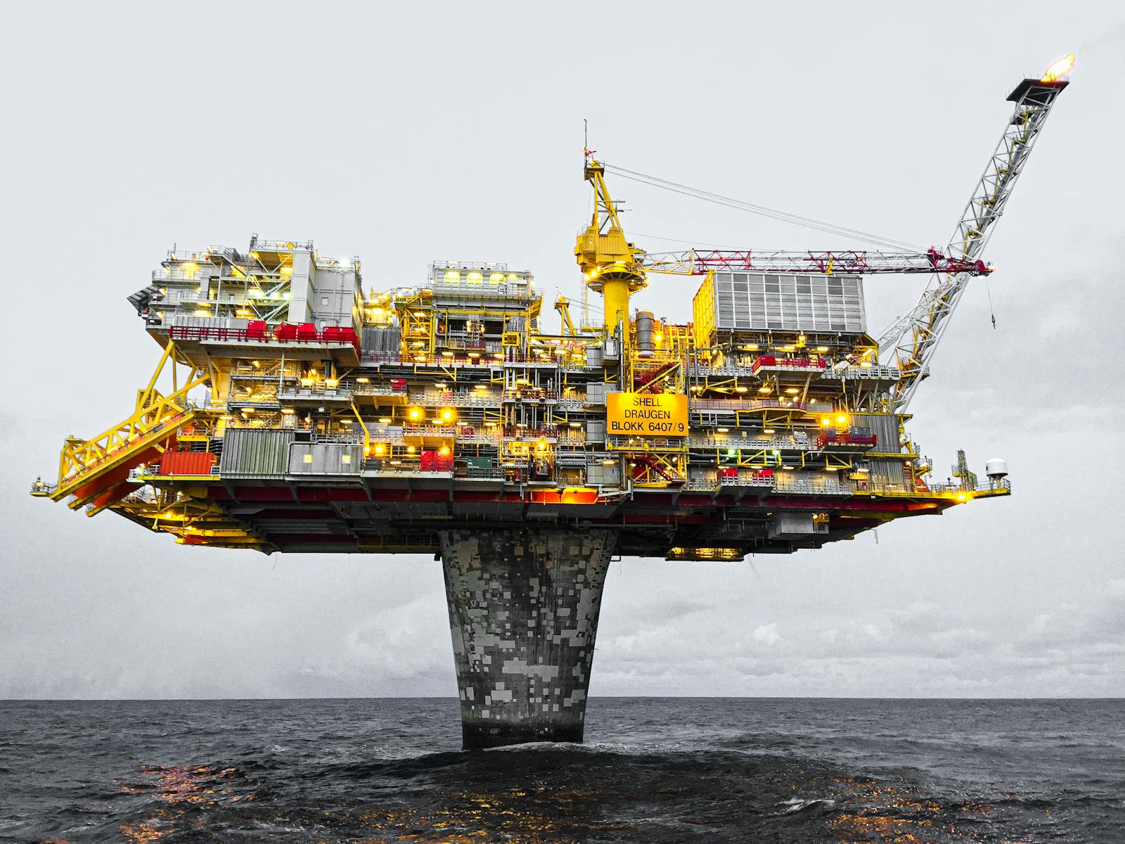 Photo by Jan-Rune Smenes Reite A well-lit offshore oil platform against a cloudy sky in Norway's waters.