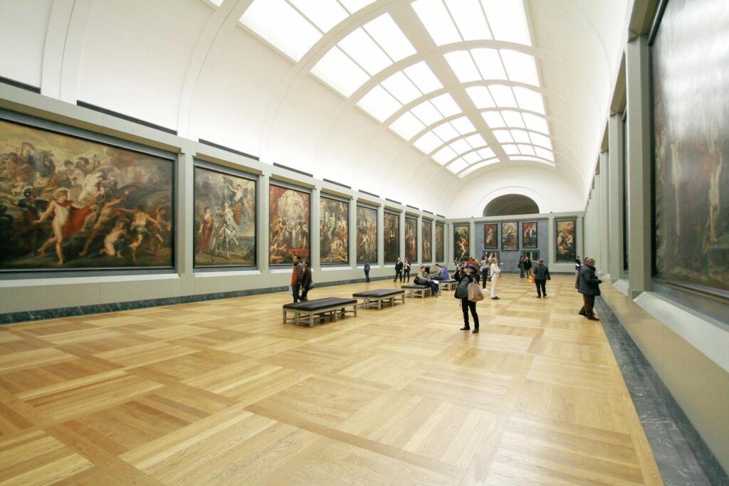 Photo by Riccardo A wide view of a museum hall showcasing famous paintings and visitors exploring the art.